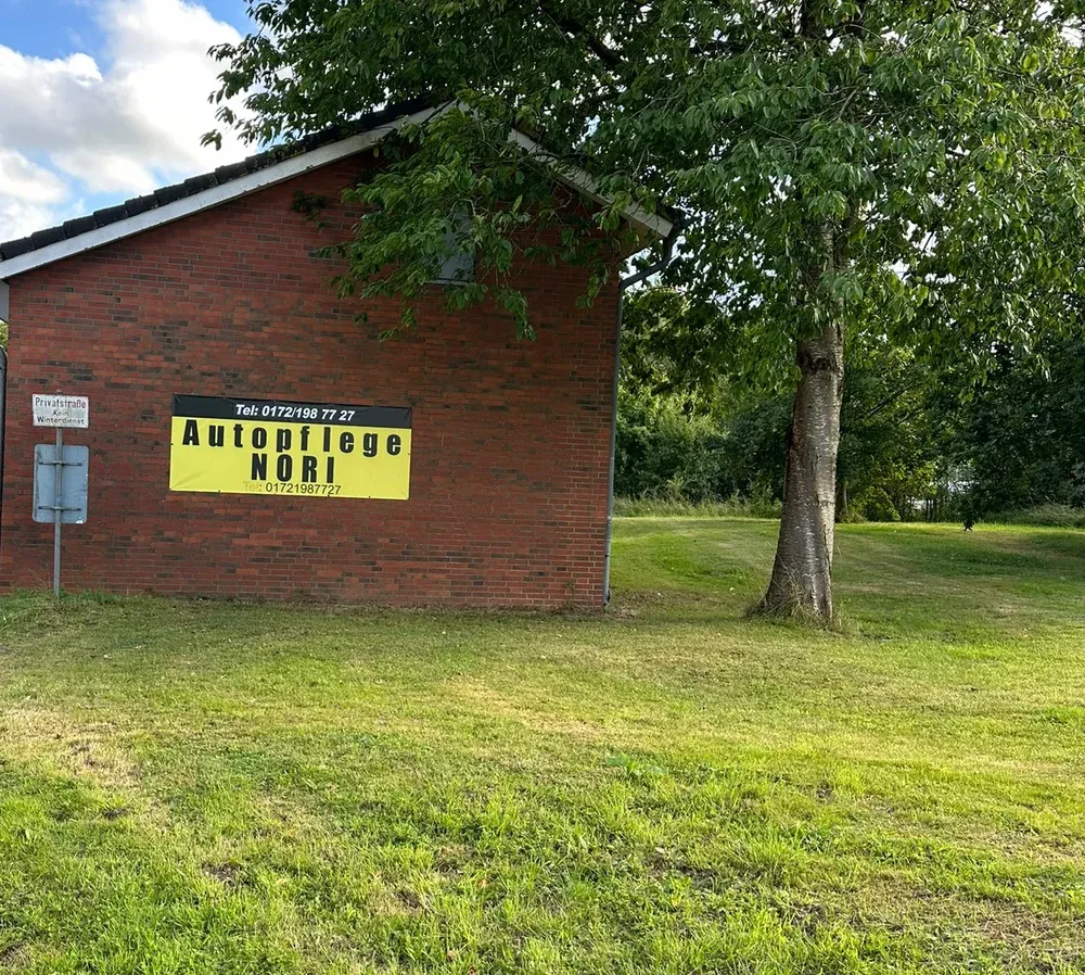 Backsteingebäude mit der gelben Autopflege-NORI-Beschilderung